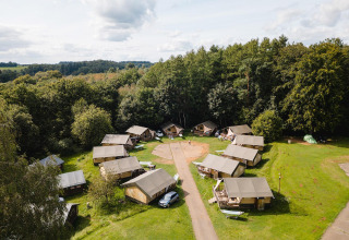 Vista aérea de tiendas safari Villatent Outback en Camping La Colline, Bélgica, rodeadas de bosque.
