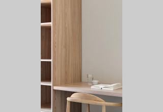 Escritorio minimalista con estantería, silla, vaso de agua, taza y libro en Waterlodge Workation, Países Bajos.