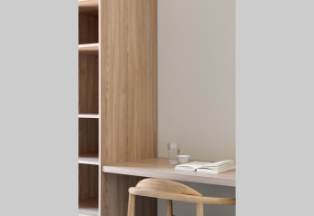 Minimal workspace with wooden desk, open shelf, chair, glass of water, cup, and book at Waterlodge Workation.