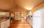 Interieur van safari tent Villatent Wood met keuken, kasten en eetgedeelte op Camping Le Pech Charmant.