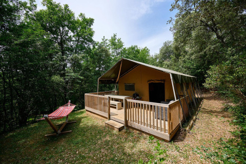 Tienda safari Villatent Wood con terraza de madera y hamaca en el bosque de Camping Le Pech Charmant, Francia