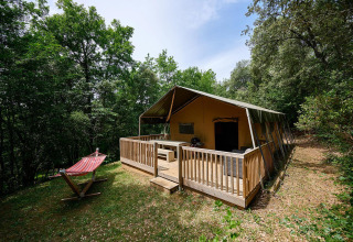 Tienda safari Villatent Wood con terraza de madera y hamaca en el bosque de Camping Le Pech Charmant, Francia