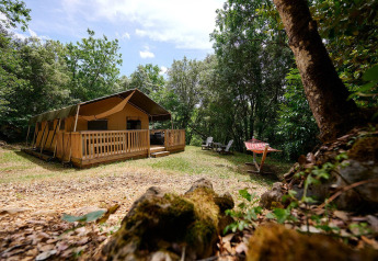 Safari-Zelt Villatent Wood auf Camping Le Pech Charmant in Frankreich, umgeben von Bäumen in der Natur.