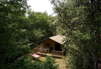 Das Safari-Zelt Villatent Wood auf Camping Le Pech Charmant in Frankreich, umgeben von grünen Bäumen.