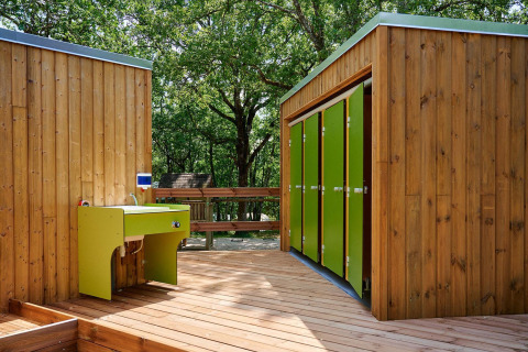 Edificios de madera con puertas verdes y fregadero exterior en Villatent Wood, Camping Le Pech Charmant.