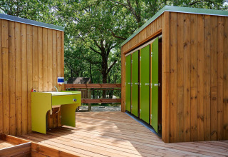 Edificios de madera con puertas verdes y fregadero exterior en Villatent Wood, Camping Le Pech Charmant.