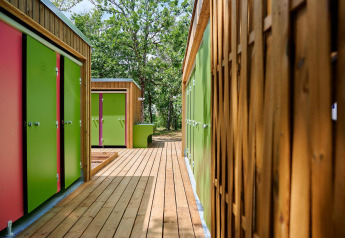 Bunte Türen und Holzstege bei Villatent Wood auf Camping Le Pech Charmant in Frankreich im Freien.