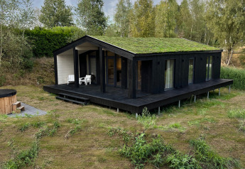 Moderne tiny house 'The Hills' med græs på taget, hot tub og sauna i naturskønne Wilsumer Berge, Tyskland.