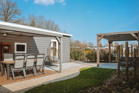 Blick auf die Terrasse und den Garten der Veluwelodge XL im Ferienpark De Boshoek in den Niederlanden.