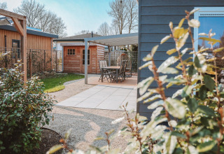 Buitenpatio bij Veluwelodge XL in vakantiepark De Boshoek, Nederland, met zitgedeelte en tuin.