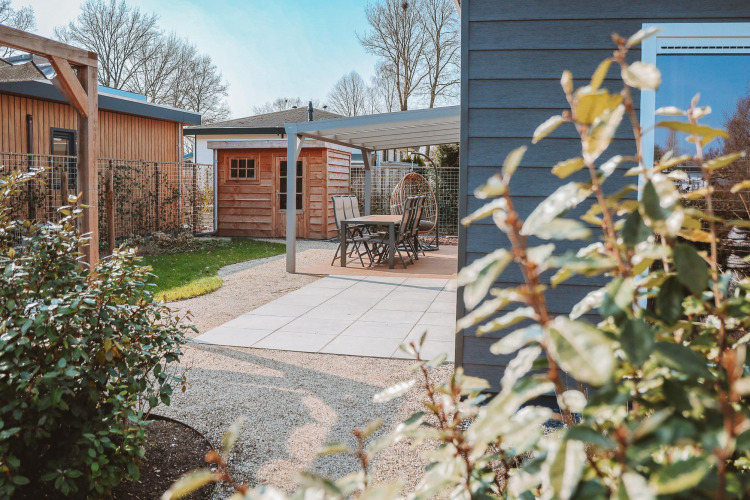 Terrasse im Freien bei Veluwelodge XL im Ferienpark De Boshoek, Niederlande, mit Garten und Sitzbereich.