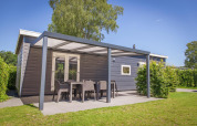 Udendørsbillede af Veluwelodge XL med overdækket terrasse og havemøbler i ferieparken De Boshoek.