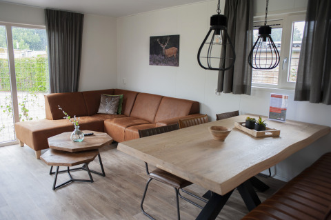 Sala moderna en Veluwelodge XL del Holiday park De Boshoek, Países Bajos, con sofá de cuero y mesa de madera.