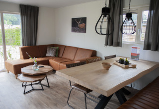 Sala moderna en Veluwelodge XL del Holiday park De Boshoek, Países Bajos, con sofá de cuero y mesa de madera.