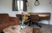 Woonruimte in Veluwelodge XL met bruine leren zitplaatsen, houten tafel en moderne verlichting.