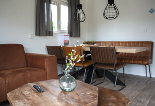 Zona giorno nella Veluwelodge XL con sedute in pelle marrone, tavolo in legno e illuminazione moderna.