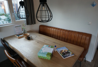 Eethoek in Veluwelodge XL, vakantiepark De Boshoek, Nederland, met lederen zitbank en houten tafel.