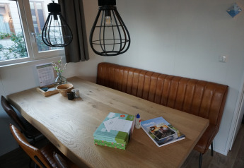 Dining area inside Veluwelodge XL at Holiday park De Boshoek, Netherlands, featuring a leather bench and table.