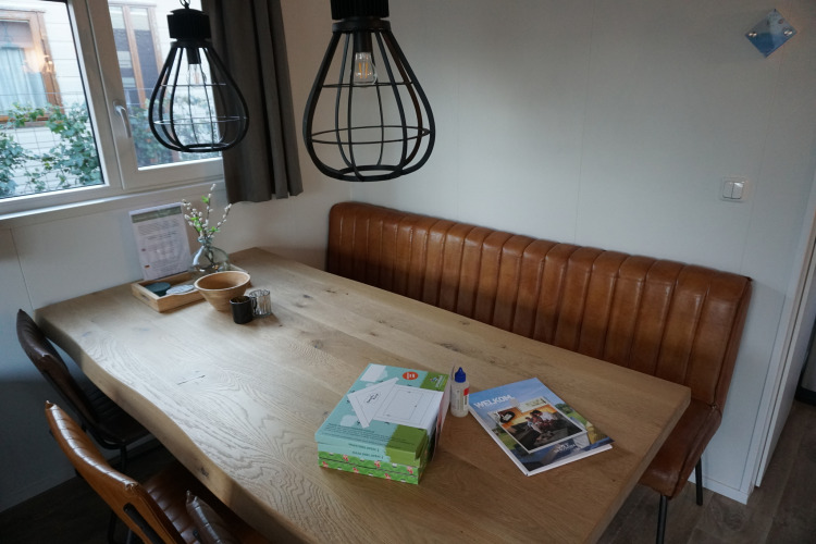 Essbereich in der Veluwelodge XL, Ferienpark De Boshoek, Niederlande, mit Ledersitzbank und Holztisch.