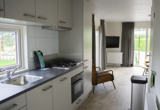 Moderne keuken en woonkamer in Veluwelodge XL op Vakantiepark De Boshoek, Nederland, met uitzicht buiten.