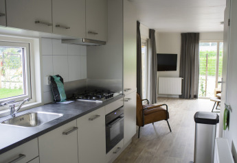 Moderne Küche und Wohnzimmer der Veluwelodge XL im Ferienpark De Boshoek, Niederlande, mit Ausblick.