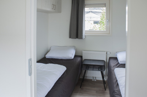 Kamer in Veluwelodge XL op vakantiepark De Boshoek in Nederland met twee eenpersoonsbedden en een raam.