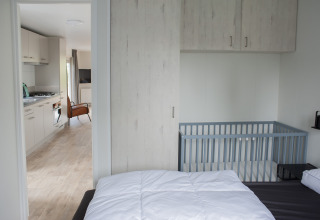 Slaapkamer met ledikant en uitzicht op keuken en woonkamer in Veluwelodge XL bij De Boshoek, Nederland.