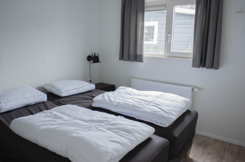 Bedroom in Veluwelodge XL at Holiday park De Boshoek, Netherlands, two single beds and window view.