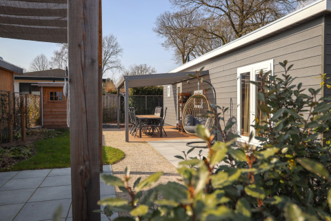 Buitenruimte bij Veluwelodge XL op vakantiepark De Boshoek, Nederland, met terras, zitje en hangstoel.