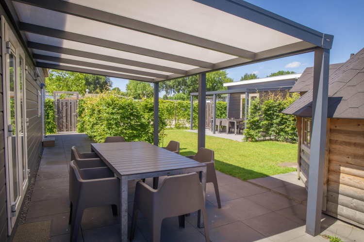 Überdachte Terrasse mit Esstisch an der Veluwelodge XL im Holiday park De Boshoek in den Niederlanden.