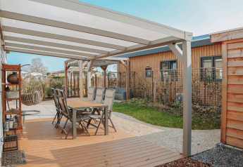 Überdachte Terrasse mit Esstisch und Stühlen an der Veluwelodge XL im Ferienpark De Boshoek, Niederlande.