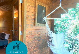 Azalea Cabin ved Glamping de Cerveira i Portugal med hængestol på veranda og hyggeligt interiør.