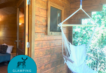 Azalea Cabin ved Glamping de Cerveira i Portugal med hængestol på veranda og hyggeligt interiør.