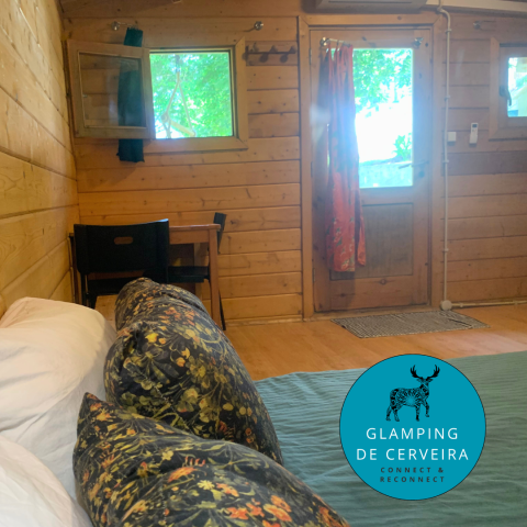 Vista interior de la Azalea Cabin en Glamping de Cerveira, Portugal, con paredes de madera y decoración acogedora.