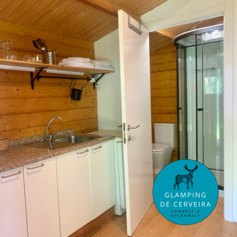 Vista interior de la cabaña Azalea en Glamping de Cerveira, Portugal, con cocina y baño modernos.