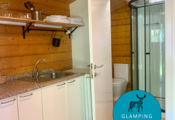 Vue intérieure de la cabane Azalea au Glamping de Cerveira au Portugal, avec coin cuisine et salle de bain.