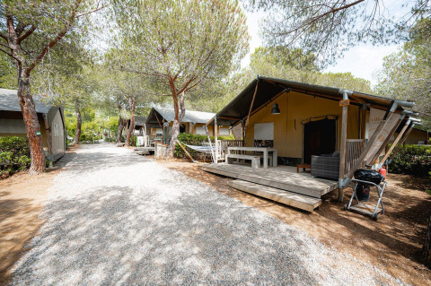 Safari tent Villatent Wood at Camping Casa dei Prati in Italy, featuring a wooden deck and surrounded by trees.