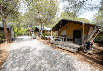 Tenda safari Villatent Wood al Camping Casa dei Prati in Italia, con veranda in legno e alberi intorno.