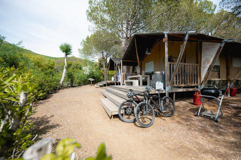 Tienda safari Villatent Wood en Camping Casa dei Prati, Italia, con terraza, bicicletas y barbacoa.