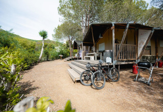 Safari tent Villatent Wood at Camping Casa dei Prati in Italy, featuring a deck, bicycles, and a barbecue.