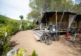 Safari tent Villatent Wood at Camping Casa dei Prati in Italy, featuring a deck, bicycles, and a barbecue.