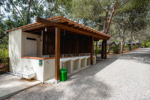 Outdoor washing station at Villatent Wood, Camping Casa dei Prati, Italy, with multiple sinks and green bin.