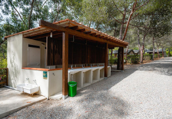 Outdoor washing station at Villatent Wood, Camping Casa dei Prati, Italy, with multiple sinks and green bin.