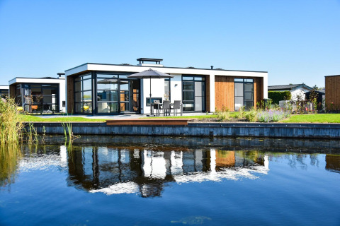 Moderna Villa Nautica junto al agua en MarinaPark Residentie Nieuw Loosdrecht, Países Bajos, bajo cielo claro.