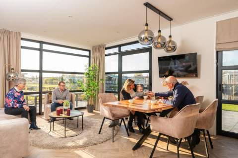 Familia compartiendo tiempo juntos en una cómoda cabaña, con gran ventanal y ambiente moderno y cálido.