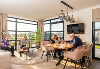 Familie verbringt Zeit zusammen in einer Lodge mit modernen Möbeln und großen Fenstern im Wohnzimmer.