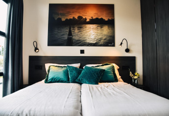 Cama moderna con cojines verdes y arte de pared en Villa Nautica, MarinaPark Residentie Nieuw Loosdrecht, Países Bajos.