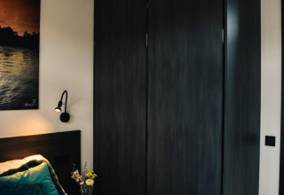 Dormitorio moderno con armario oscuro y cama en Villa Nautica, MarinaPark Residentie Nieuw Loosdrecht, Países Bajos.