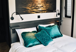 Dormitorio en Villa Nautica en MarinaPark Residentie Nieuw Loosdrecht con cama doble y cuadro de un atardecer.