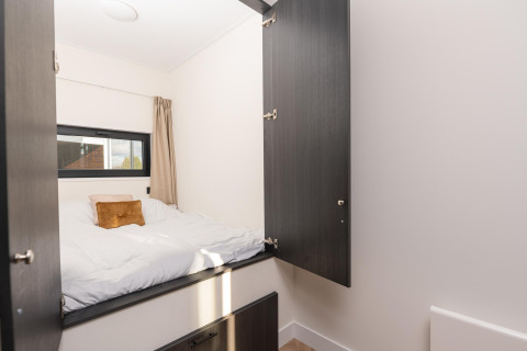 Acogedora habitación con ropa de cama blanca y armarios abiertos en Villa Nautica, MarinaPark Nieuw Loosdrecht.